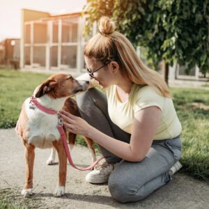 Woman kneeling with dog outdoors